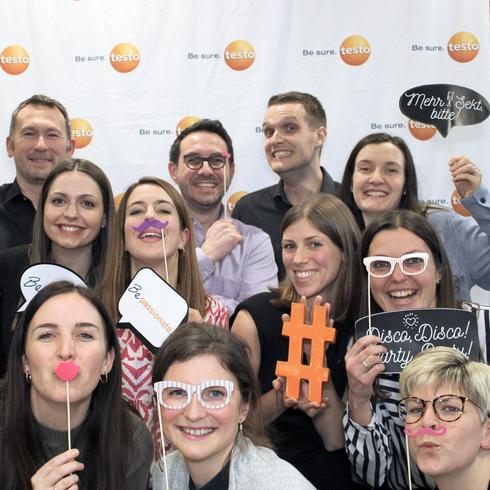Chez Testo, il existe un esprit d'équipe unique Les employés de Testo rient joyeusement dans une boîte à photos