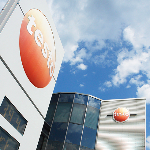 Plus de services, plus de sécurité pour l'avenir de notre entreprise Bâtiment Testo avec logo sous un ciel bleu